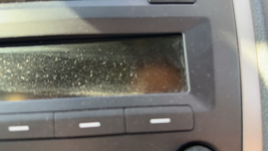 Close-up of dusty buttons and display on a car audio system, dashboard stereo controls, vehicle entertainment equipment, automotive interior detail.