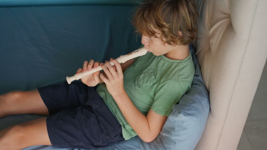 A little boy learns to play the flute at home, practicing with focus and enthusiasm in a cozy, warm setting. A charming scene of early musical exploration, creativity, and childhood growth.