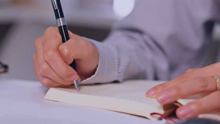 Writing Hand Holding Pen Above Paper Notebook for Focused Office Work, Professional Handwriting, Business Document Note Creation, Close Up Workspace Activity with Black Pen and Paper Detail