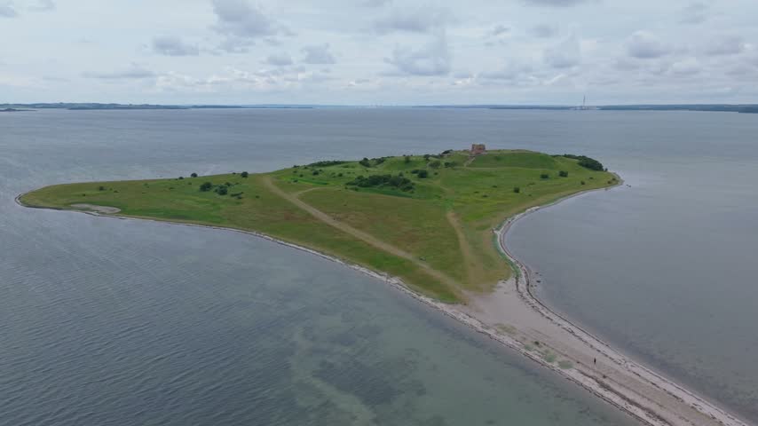 Drone orbit above the historic Kalo Castle Ruins on a cloudy day, showcasing the medieval fortress and the scenic coastal landscape of Eastern Jutland, Denmark.