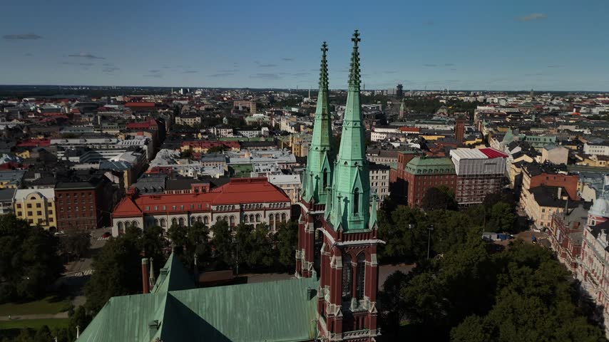 Drone footage of St Johns Church rising above the Helsinki cityscape with surrounding rooftops streets trees and dense urban development