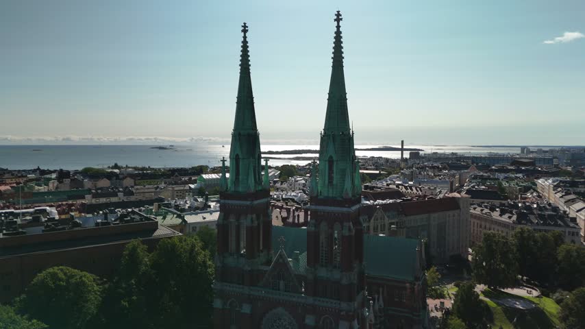 Aerial drone shot of St Johns Church standing prominently within the Helsinki cityscape surrounded by historic buildings residential blocks and green urban spaces