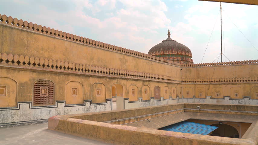 Wide static shot showing yellow fort walls, parapets, and decorative dome roof at Nahargarh Fort in Jaipur, Rajasthan, India.