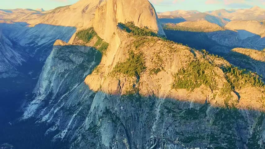 Golden sunset light glows across the panoramic view of Half Dome from Glacier Point in Yosemite National Park
