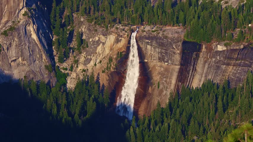 Granite cliffs and Nevada Fall in Yosemite Valley caught in golden sunset light from Glacier Point viewpoint California