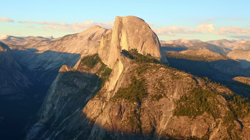 Golden sunset light glows across the panoramic view of Half Dome from Glacier Point in Yosemite National Park