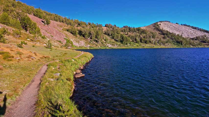 Scenic panoramic view of Middle Gaylor Lake reflecting the warm golden light of sunset in Yosemite National Park, California