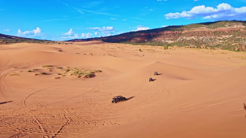 Golden sunset light bathes sweeping reddish sand ridges and desert terrain from atop a massive dune in Coral Pink Sand Dunes State Park