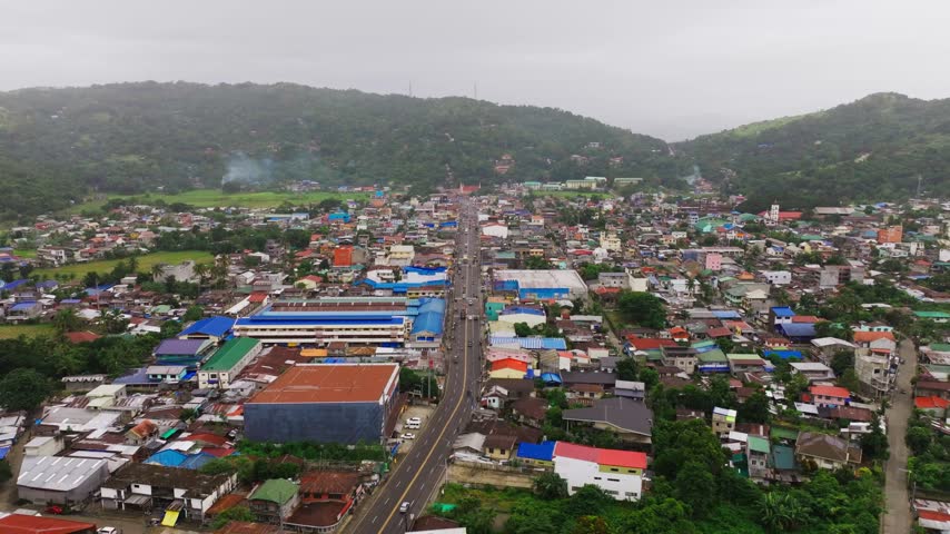 Drone moves forward and climbs above Bambang streets toward lush mountain ridges