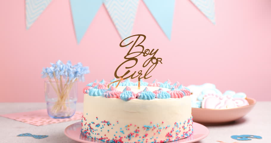 Baby gender reveal party. Tasty cake with decor and cookies on table, closeup. Camera moving in