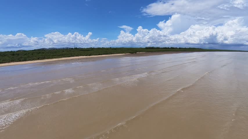 Wide, muddy river meets sandy beach under vast sky at Kuala Muda, Penang