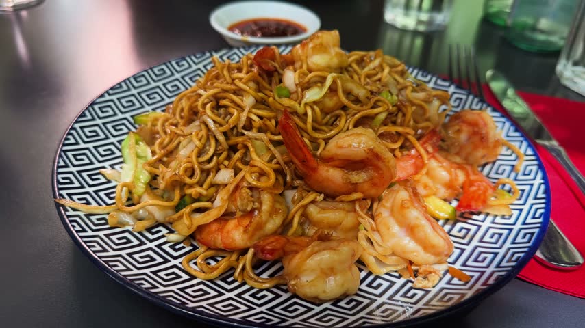 Plate of yakisoba noodles with shrimp on decorative dish, Asian stir-fried noodle dish served in restaurant. High quality 4k footage