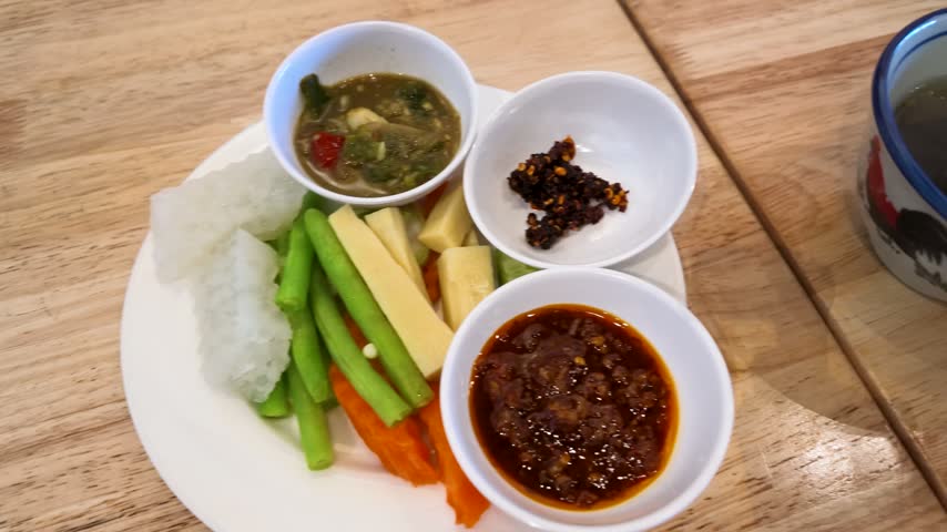 High-angle view of traditional Burmese chili dipping sauces served with fresh vegetables and soup.