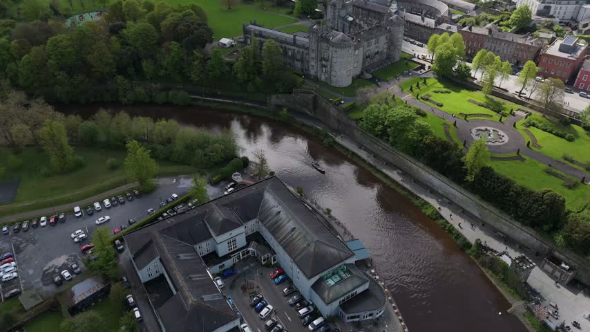 Aerial view of Kilkenny Castle and the River Nore flowing through the historic town with lush green gardens and surrounding architecture in Kilkenny, County Kilkenny, Ireland.