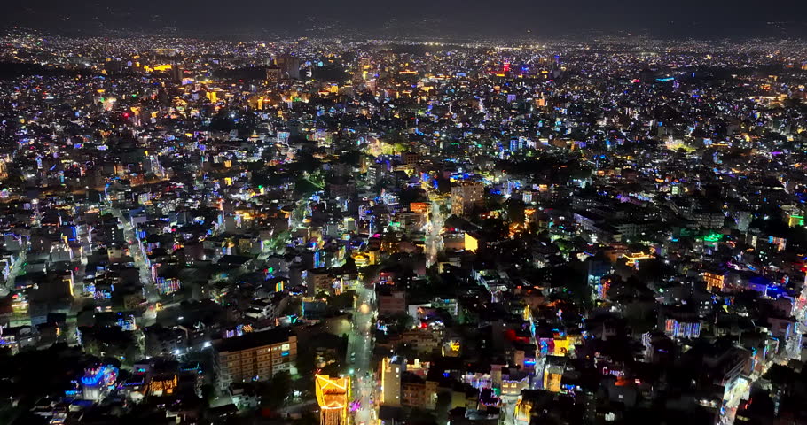 Kathmandu, Nepal, aerial shot across the expansive cityscape filled with glowing festival lights, decorated houses, and vibrant streets during Tihar night.