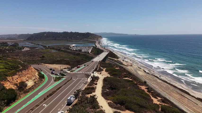 A beautiful, elevated perspective stretches from the rugged terrain of Torrey Pines across the coastline to the distant Pacific horizon. Nice view of light traffic and the small bridge.