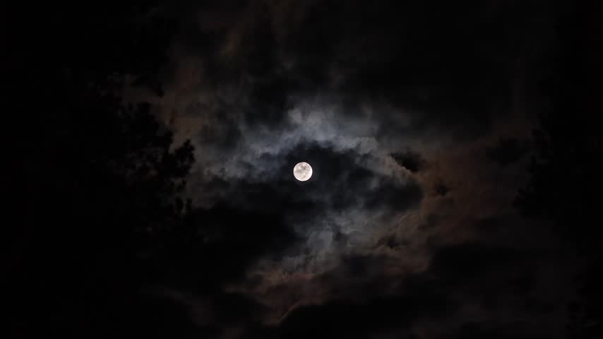 Fast Moving Dark Clouds Pass Over Bright Full Moon Creating Atmospheric Night Sky Scene Concept of Mystery and Dramatic Night Sky