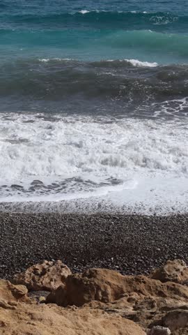 Turquoise Ocean Waves Crash Over Rocks Onto Pebble Beach In Real Time Vertical Video Concept of Summer Vacation and Travel