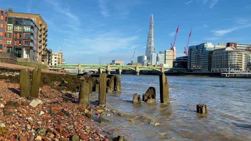 London pan across River Thames from shore to Shard Embankment