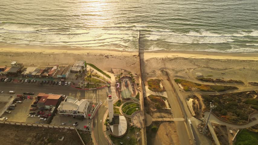Aerial drone view of US Mexico border wall extending into Pacific Ocean between Tijuana and San Diego