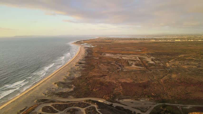Aerial drone view of US Mexico border wall extending into Pacific Ocean between Tijuana and San Diego