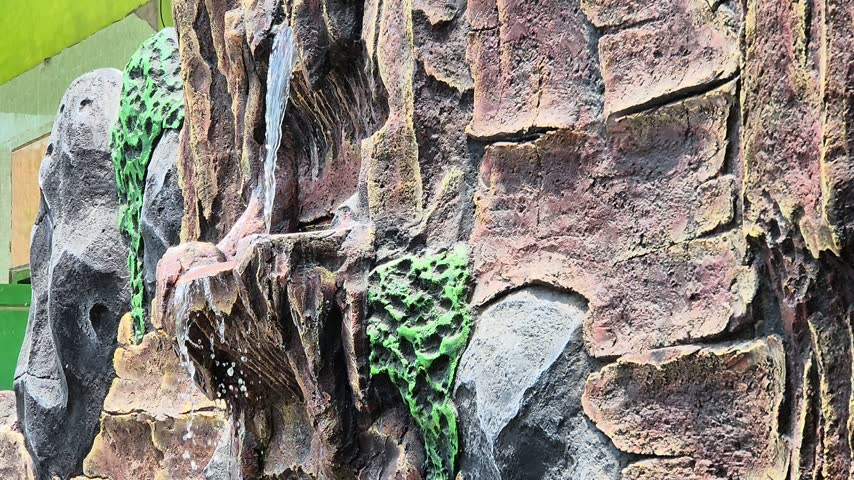 Close-up of Artificial Rock Waterfall Feature with Flowing Water in Garden