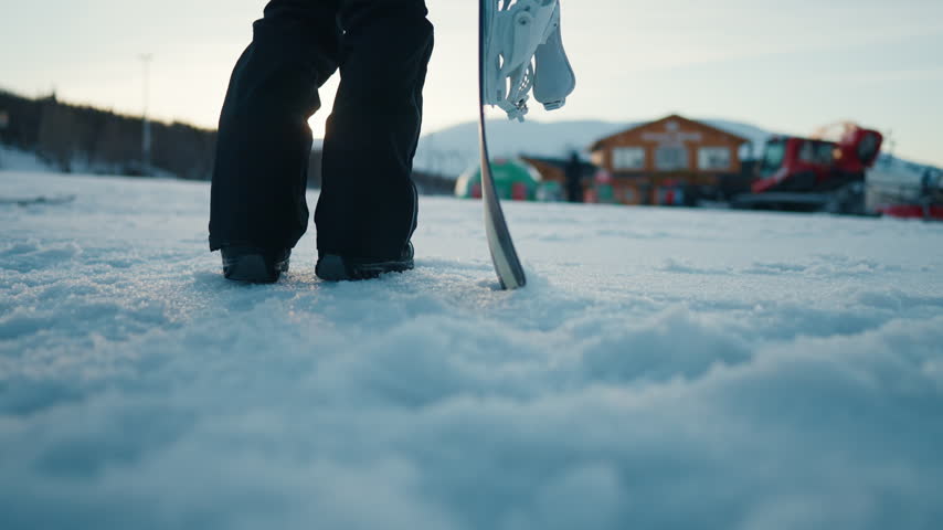 Spend winter vacation in luxury ski resort, closeup of female snowboarder legs. Athletic woman admiring beautiful mountains view from slope, details shot, white snow, calmness and solitude in highland