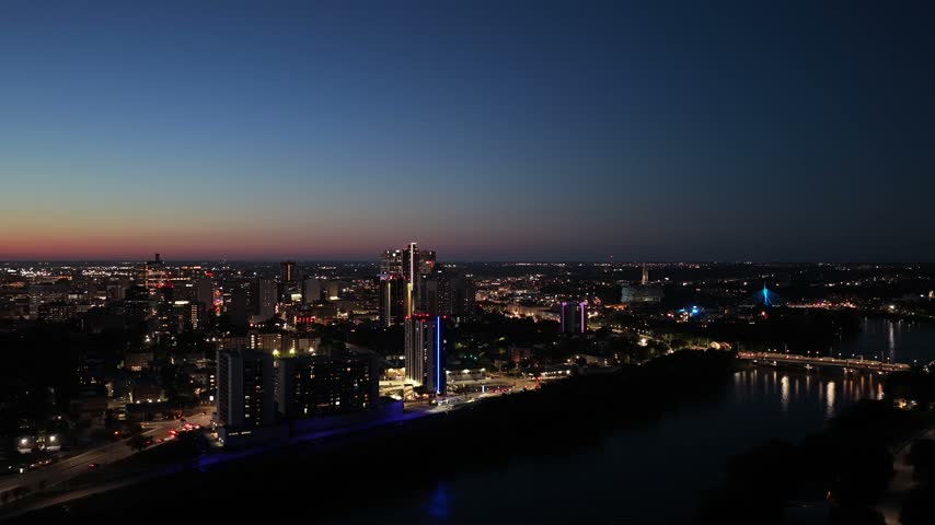 Downtown Winnipeg at dusk, gorgeous sunset glimmer with city lights, 4K aerial
