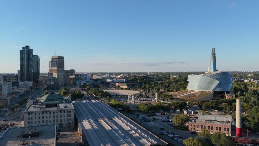 Downtown Winnipeg skyline featuring Museum for Human Rights, The Forks and VIA Rail station, 4K drone view.