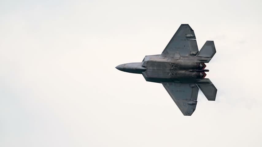An F-22 Raptor Stealth Fighter Ascends Rapidly as Vapor Condensation Envelops Its Fuselage Against an Overcast Sky.