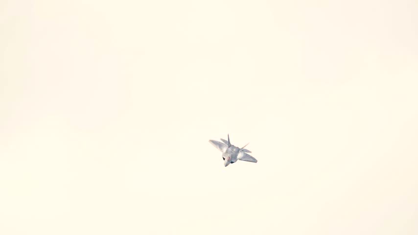 An F-22 Raptor Stealth Fighter Ascends Towards Overcast Skies With Glowing Afterburners Trail Visible.