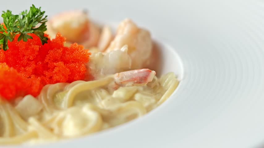 Creamy carbonara spaghetti topped with succulent shrimp and vibrant salmon roe, combining rich pasta sauce with delicate seafood flavors in an elegant dish.