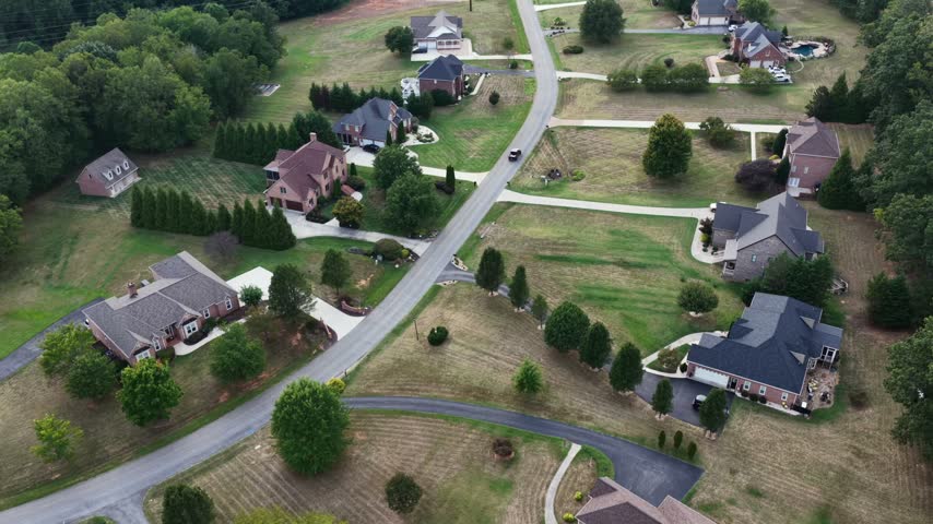 Large brick homes on generous lots line a quiet curving street with private pools and long driveways in a Forest, Virginia neighborhood. Aerial view