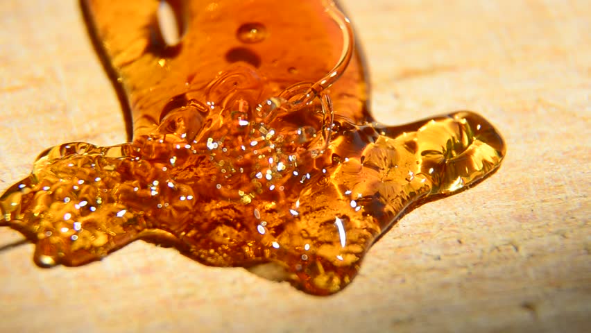 Pouring Golden Organic Honey and forming abstract arrow on wooden surface