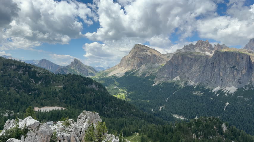 Panoramic view of Cir mountain peaks and Passo Gardena valley with green pine forest and dynamic sky in Dolomites, Italian Alps.