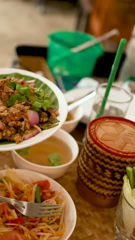 Close-up of person eating spicy minced pork salad with papaya salad and sticky rice.