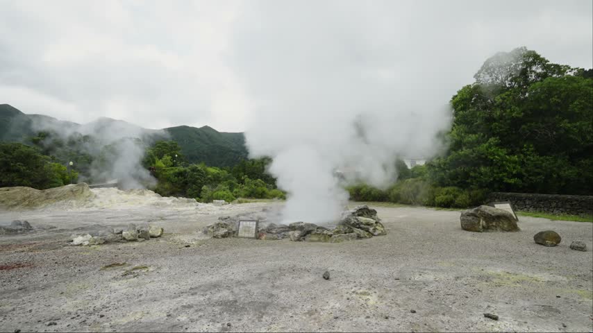 Geothermal energy source emitting thick white steam clouds into atmosphere at Furnas Valley volcanic park. Volcanic activity showing geothermal vent and hot spring landscape on overcast day in Azores.