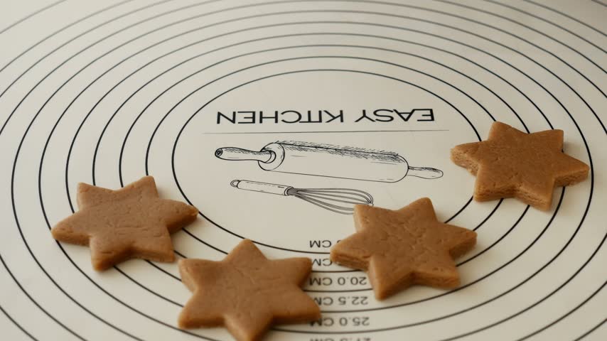Woman picking up star shaped gingerbread cookie dough during Christmas baking.