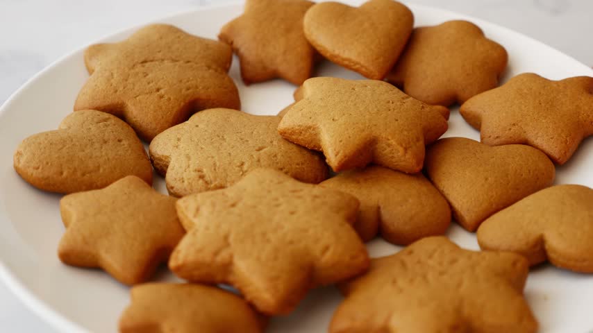 Close-up of homemade gingerbread star and heart shaped cookies on plate for Christmas holiday.