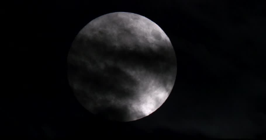 Footage of the full moon moving through the clouds at night.