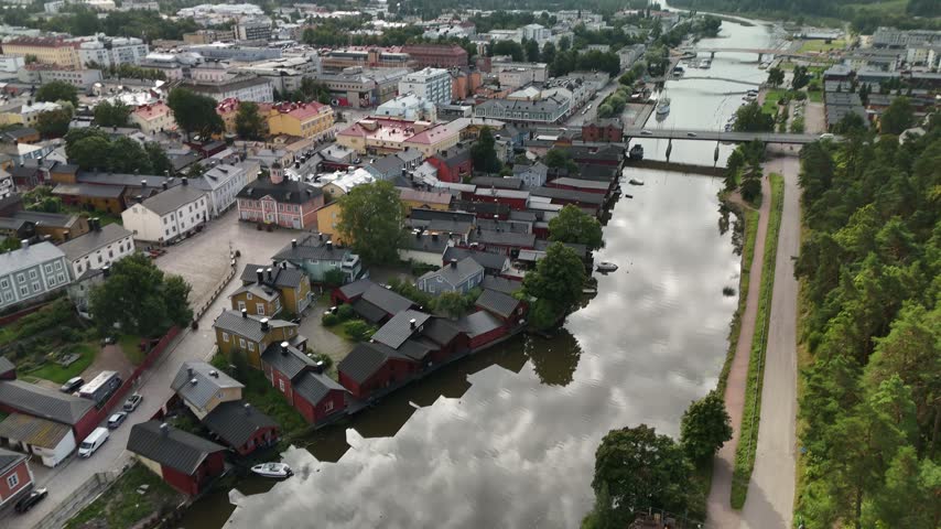 Wide aerial view of Porvoo showing the red riverfront warehouses historic old town buildings and peaceful water surrounded by the Finnish urban landscape