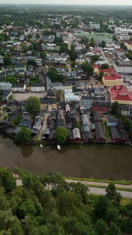 Vertical screen aerial view of Porvoo over the river with vivid red warehouses colorful wooden houses historic rooftops and peaceful waterfront scenery in Finland