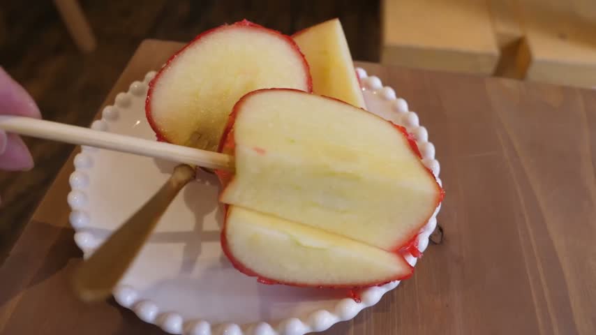 A close-up shot of a crisp apple slice coated in a vibrant, glossy red candy shell.