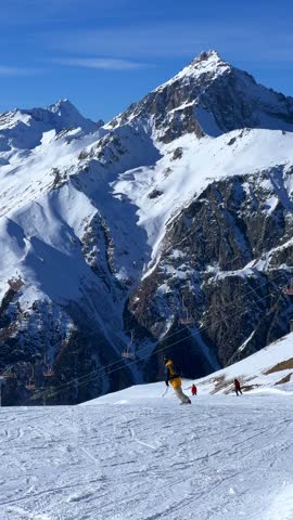 Dombay, Karachay-Cherkessia, Russia, January 9, 2025: People skiing in the ski resort. Snowboarders and skiers in winter down the mountains. Winter recreation and sports. 4K