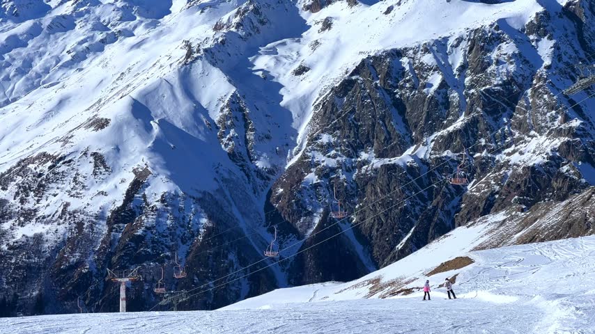 Dombay, Karachay-Cherkessia, Russia, January 9, 2025: People skiing in the ski resort. Snowboarders and skiers in winter down the mountains. Winter recreation and sports. 4K