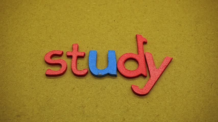 A top view of the word study formed by red and blue glitter foam alphabet letters on craft texture, symbolizing learning, school study, reading education, and childhood typography concept.