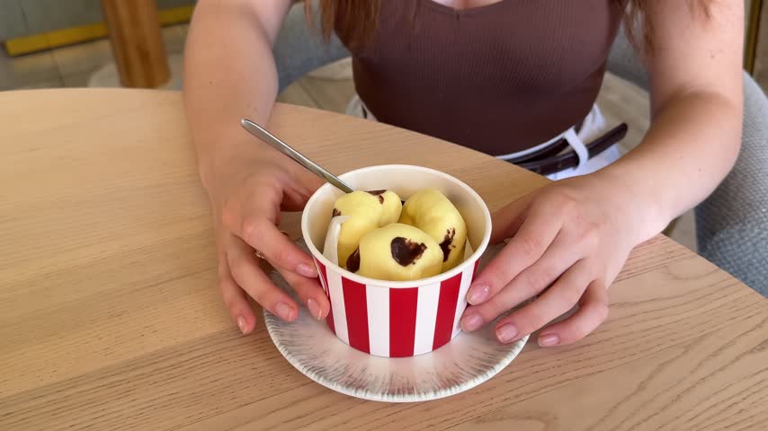 Female hands arranging a popcorn box filled with large round popcorn flavored desserts, removing one sweet piece and presenting an artistic gourmet confectionery creation