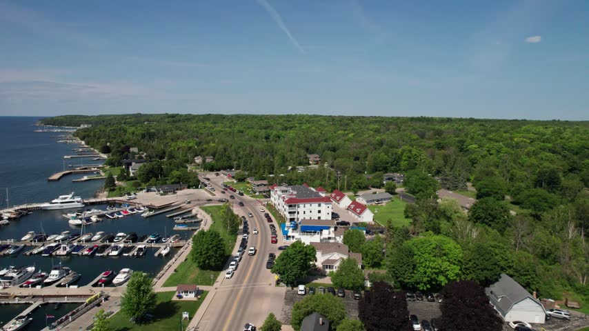 Right to Left Aerial Sister Bay in Door County Wisconsin in the summer time near the water.  Marina and Traffic Below. 