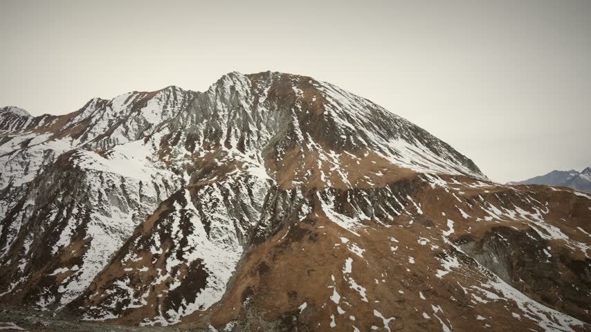 A detailed close view reveals a massive snow streaked Himalayan mountain face, rugged rock texture meeting golden autumn slopes across this far west Nepal peak.