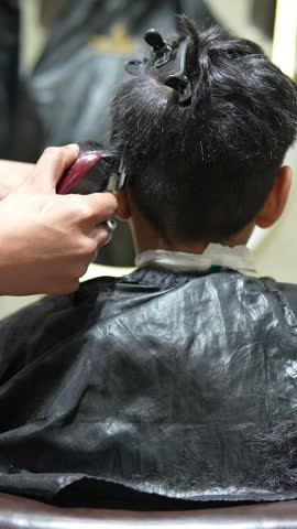 Professional Barber Giving a Haircut to a Young Male Client in a Modern Salon, Close Up View of Hair Clipping and Grooming Service